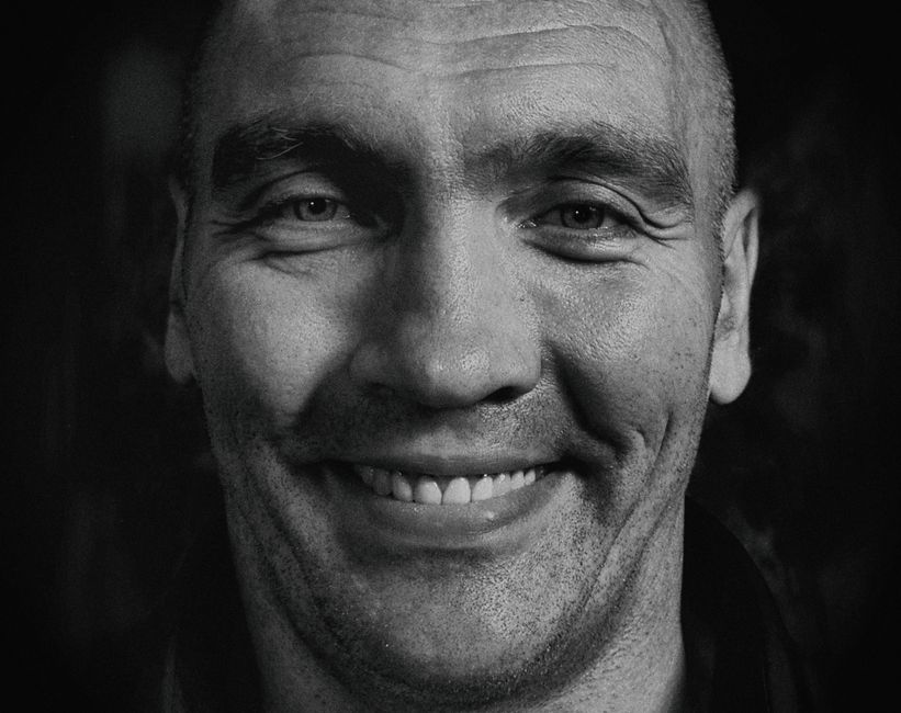Close-up portrait of a smiling man with a joyful expression in black and white.