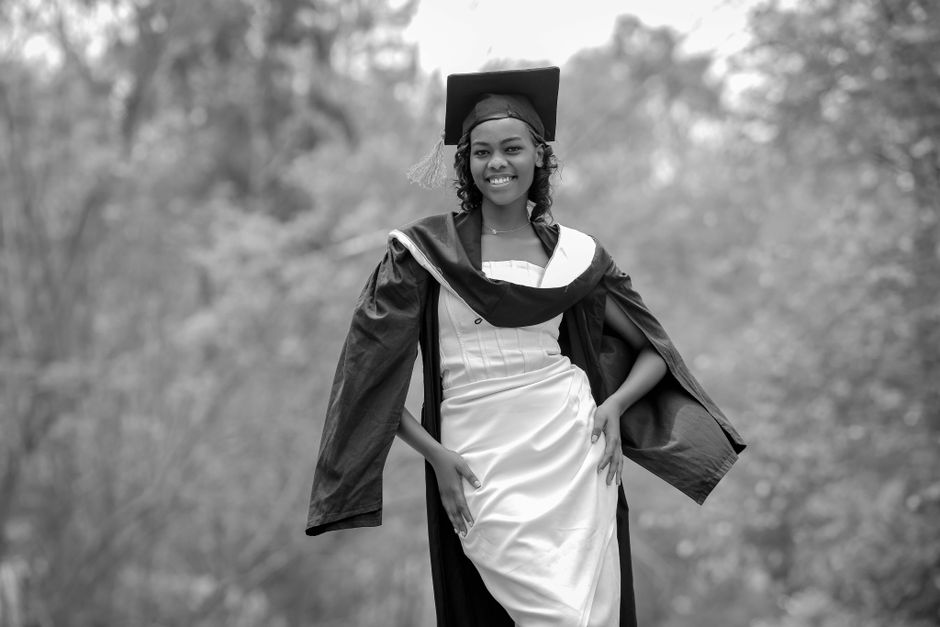 Black and white outdoor portrait of a young graduate in Rwanda.