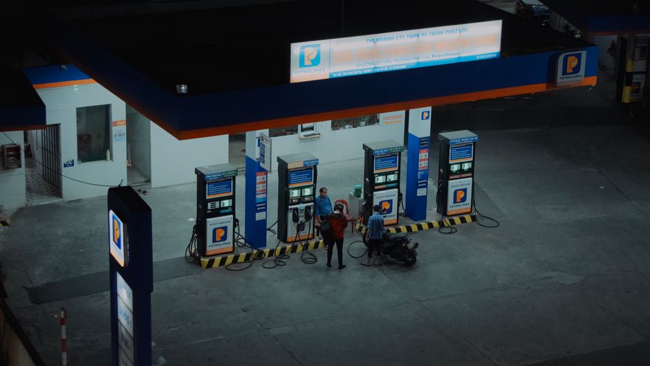 Aerial view of a gas station with people fueling motorcycles at night.