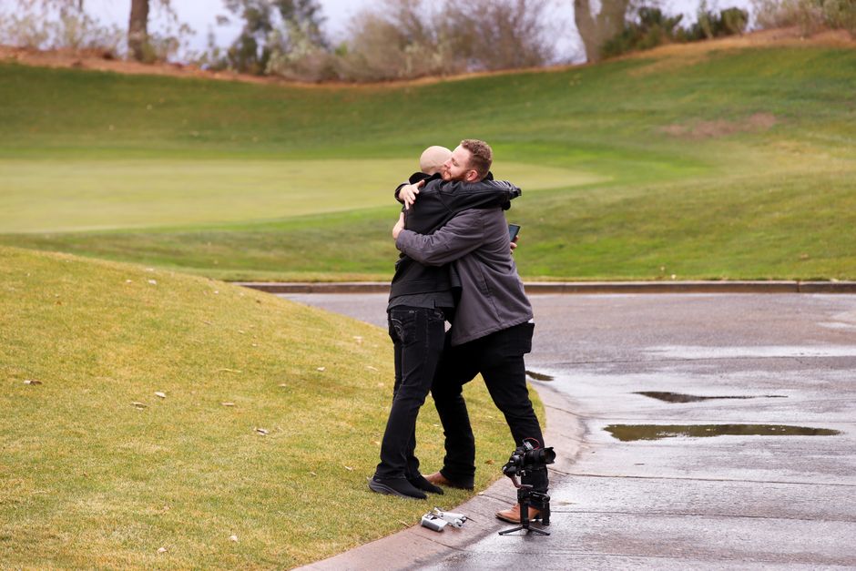 Two men hugging outdoors on a rainy day, showcasing friendship and connection.