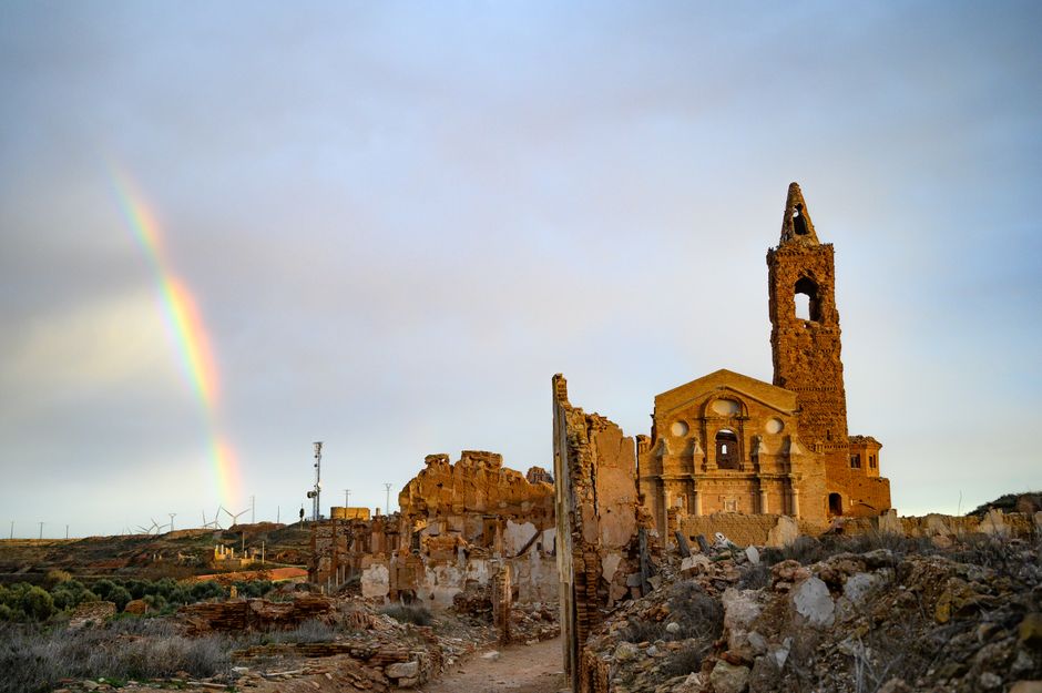 Scenic view of Belchite's historic ruins with a rainbow arching over the landscape.