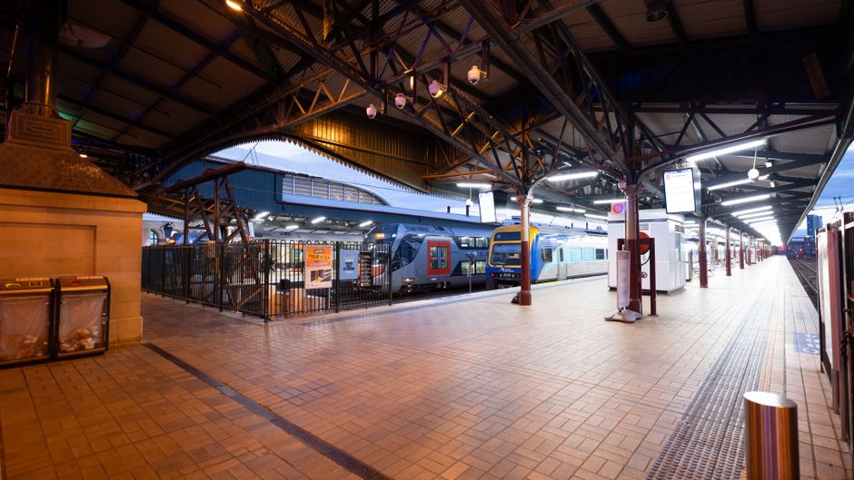 Wide view of Central Railway Station platform in Sydney at dusk with trains and architectural details.