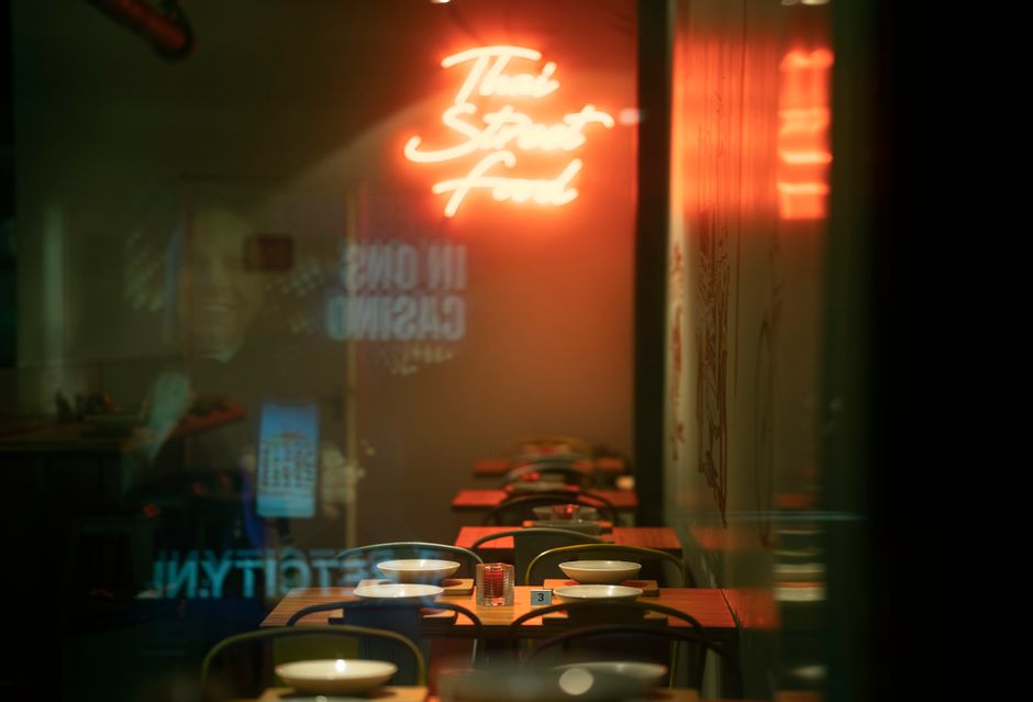 Inviting interior of a Thai street food cafe with neon signs and cozy table settings.