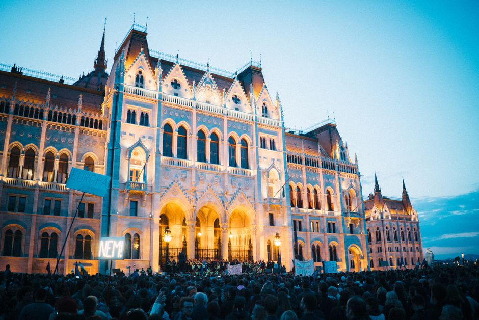 Crowd of protesters gathered in front of the historic Budapest Parliament Building during the evening.