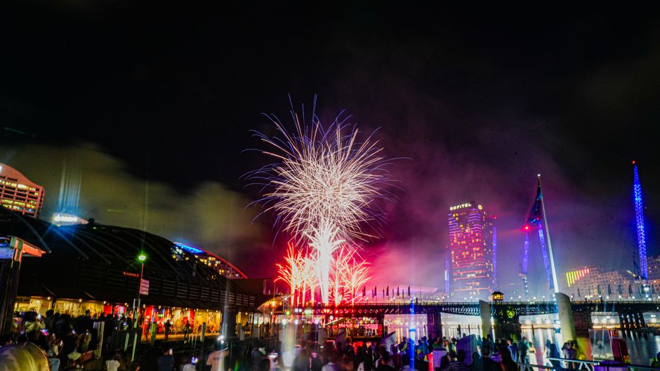 Vibrant fireworks illuminate the night sky over the city skyline, creating a festive atmosphere.