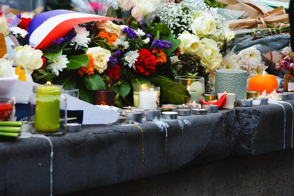 A serene memorial setup with candles and floral tributes on a stone surface outdoors.
